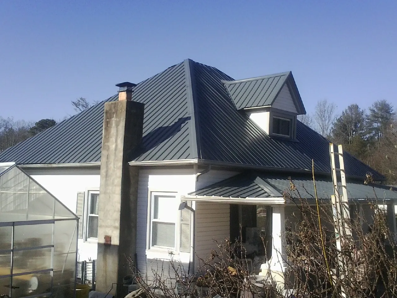 Dark blue standing seam metal roof on a white farmhouse with dormer — Slate & Tile Roof Repair by Roofing Brothers in Ulm