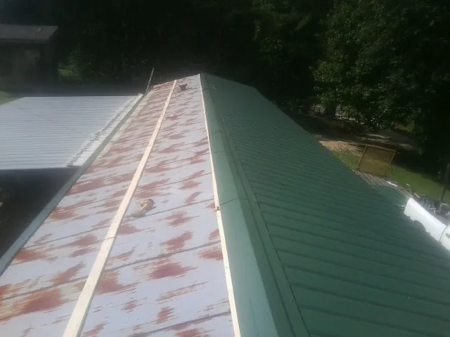 Old rusted panels beside newly installed green metal roofing — Wind Damage Roof Repair by Roofing Brothers in Ulm