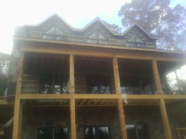 Dormers and porch framing on a large log home under construction — Roof Coating work by our crew in Ulm