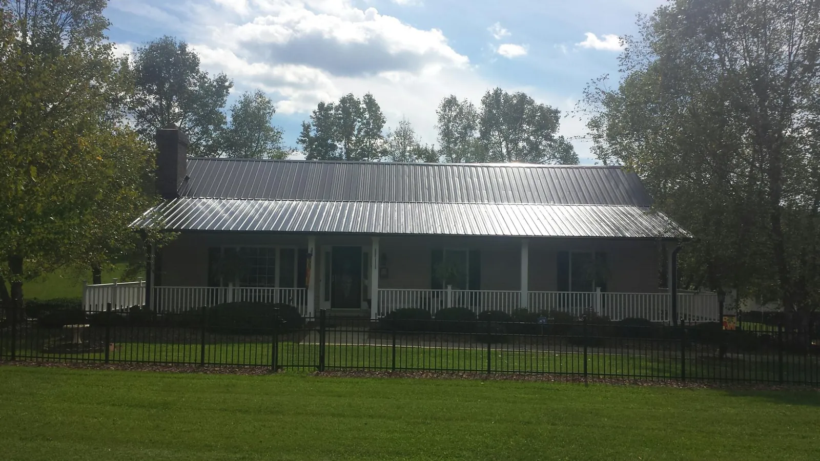 Gray metal roof on a brick ranch with a full width front porch — Gutter Guard Installation work by our crew in Ulm